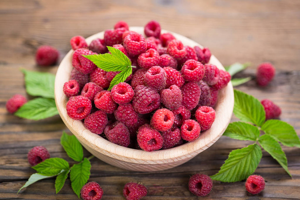 fresh and ripe raspberries in bowl on wooden surface - Foto, Bild