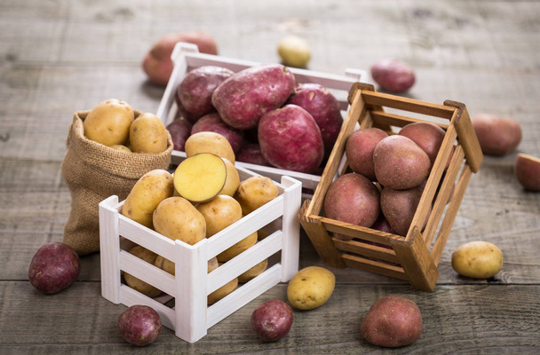 close up view of raw potatoes on wooden background - Фото, зображення