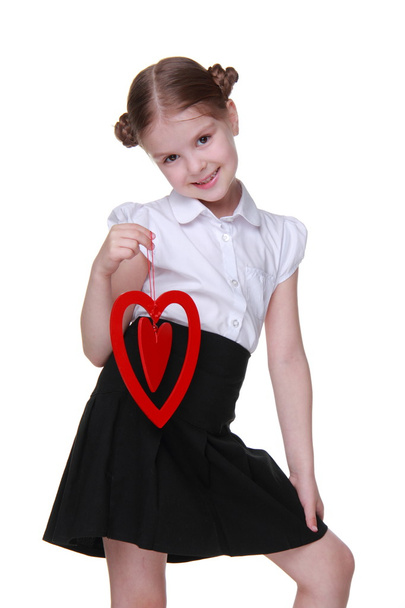 Caucasian lovely schoolgirl holding red heart symbol - Foto, Imagem
