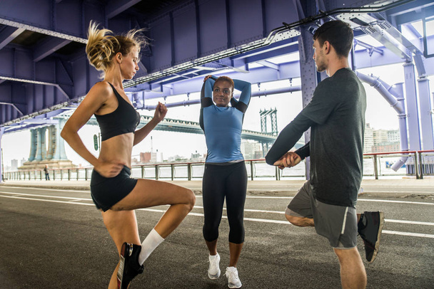 Multi-ethnic group of runners training outdoors - Sportive people running on the street of Manhattan, concepts about sport and healthy lifestyle - Foto, Bild