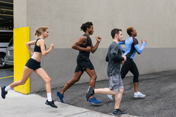 Multi-ethnic group of runners training outdoors - Sportive people running on the street of Manhattan, concepts about sport and healthy lifestyle - Foto, afbeelding