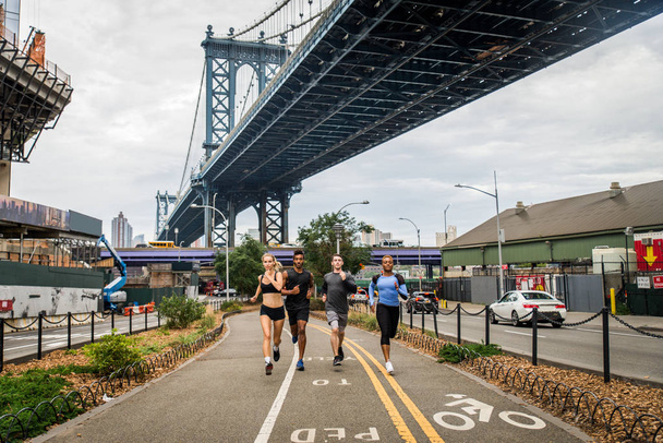 Multi-ethnic group of runners training outdoors - Sportive people running on the street of Manhattan, concepts about sport and healthy lifestyle - Fotografie, Obrázek