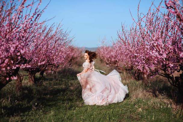 Beautiful young girl under the flowering pink spring tree - Foto, Imagen
