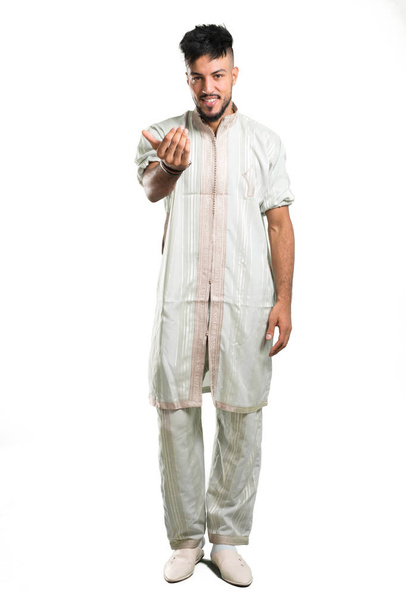 A full-length shot of a Arabic young man wearing typical arab clothes presenting and inviting to come on isolated white background - Foto, imagen