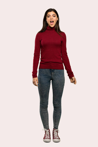 A full-length shot of a Teenager girl with turtleneck with surprise facial expression over isolated background - Photo, Image