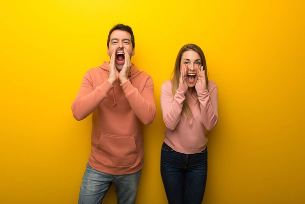 Group of two people on yellow background shouting and announcing something - Photo, Image