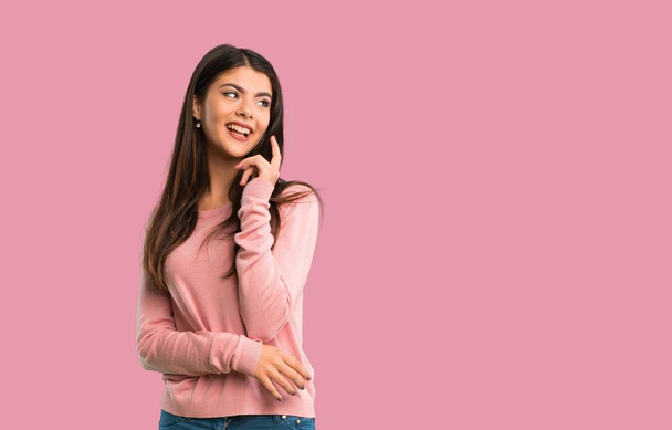 Teenager girl with pink shirt thinking an idea while looking up on isolated pink background - Foto, Imagem