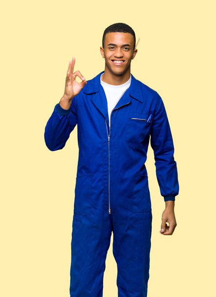 Young afro american worker man showing an ok sign with fingers on isolated background - Photo, Image