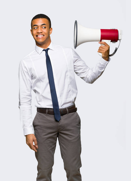 Young afro american businessman taking a megaphone that makes a lot of noise on isolated background - Фото, зображення