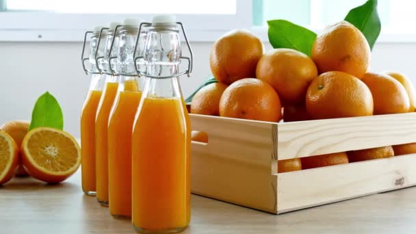 pile of fresh oranges in wooden box and glasses of juice - Footage, Video