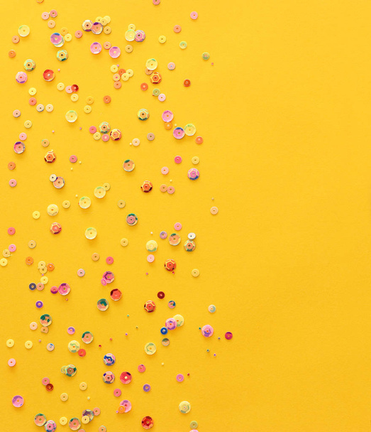 pastel colorful sequins on a yellow paper. Decorative accessories for sewing and party. Blank background with space for text - Fotografie, Obrázek