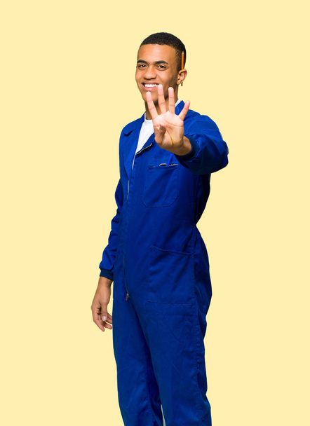 Young afro american worker man happy and counting four with fingers on isolated background - Фото, зображення