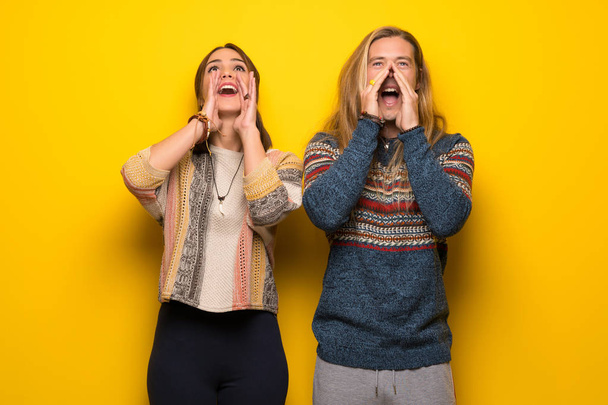 Hippie pareja sobre amarillo fondo gritando y anunciando algo
 - Foto, imagen