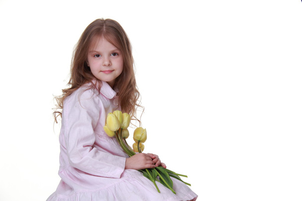 χαριτωμένο μικρό κορίτσι σε ένα φόρεμα με ένα μπουκέτο με τουλίπες - Φωτογραφία, εικόνα