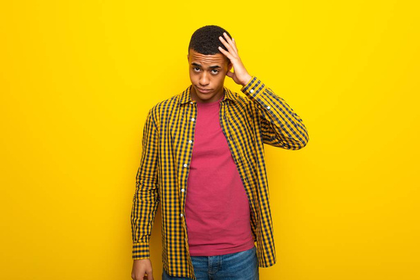 Joven afroamericano sobre fondo amarillo con expresión de frustración e incomprensión
 - Foto, Imagen