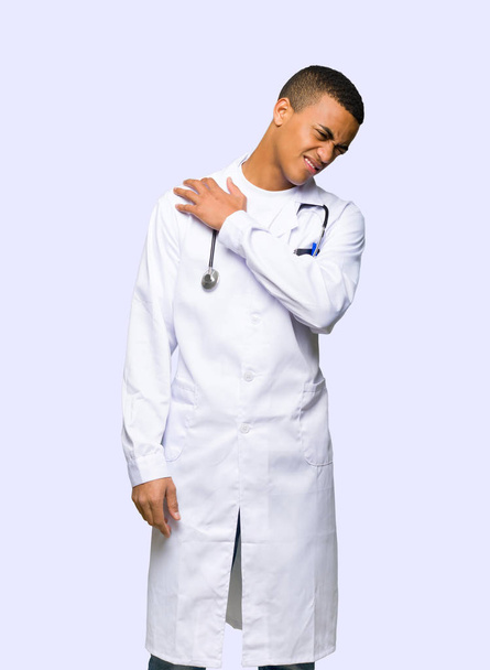 Joven médico afroamericano que sufre de dolor en el hombro por haber hecho un esfuerzo sobre un fondo aislado
 - Foto, imagen