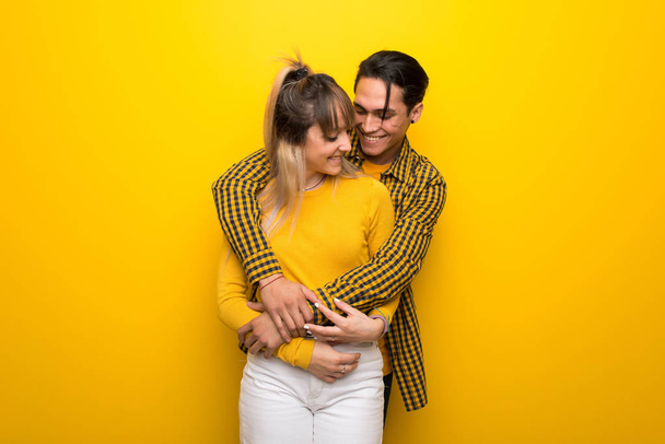 Canlı sarı arka planda sarılayan genç çift - Fotoğraf, Görsel