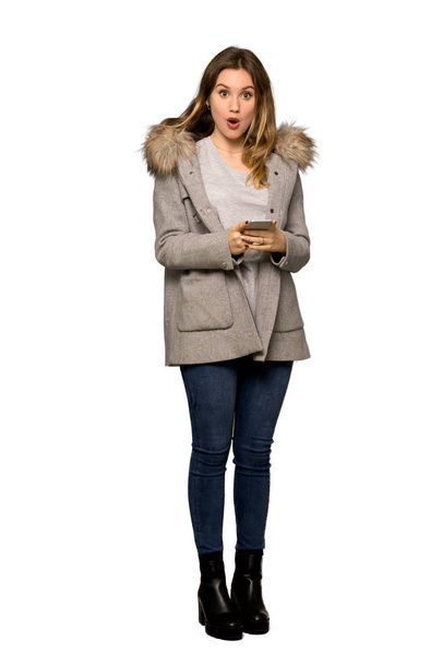 Un plan complet d'une adolescente avec manteau envoyant un message avec le mobile sur fond blanc isolé
 - Photo, image