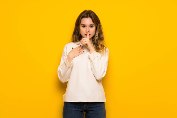 Menina adolescente sobre a parede amarela mostrando um sinal de silêncio gesto colocando o dedo na boca
 - Foto, Imagem