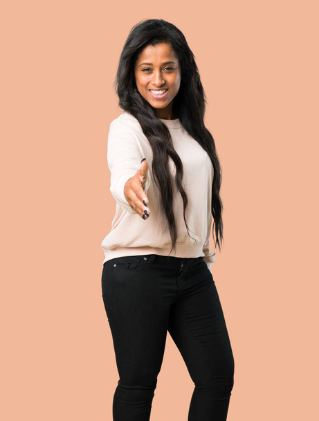 Young afro american woman shaking hands for closing a good deal on isolated brown background - Photo, Image