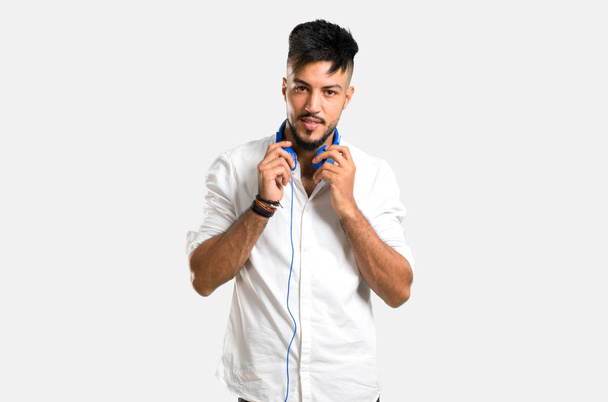 Άραβας νεαρός άνδρας με λευκό πουκάμισο ακούγοντας μουσική με ακουστικά σε γκρι φόντο - Φωτογραφία, εικόνα