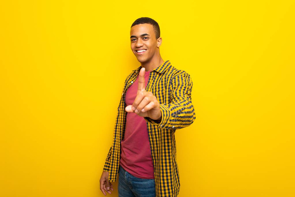 Jeune homme afro-américain sur fond jaune montrant et levant un doigt
 - Photo, image