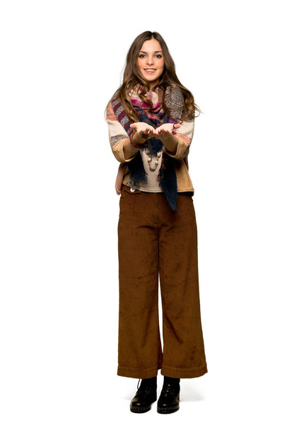 Tiro completo de Jovem hippie mulher segurando copyspace imaginário na palma da mão para inserir um anúncio no fundo branco isolado
 - Foto, Imagem