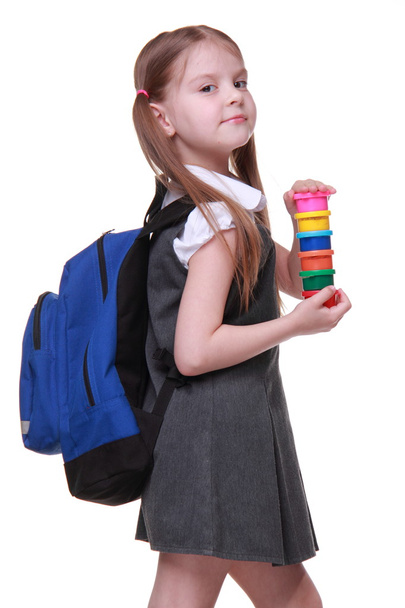 Cute schoolgirl with schoolbag holding paints - Fotó, kép