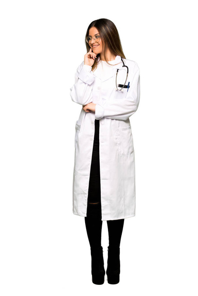 Cuerpo completo de una joven doctora mirando hacia un lado con la mano en la barbilla
 - Foto, imagen