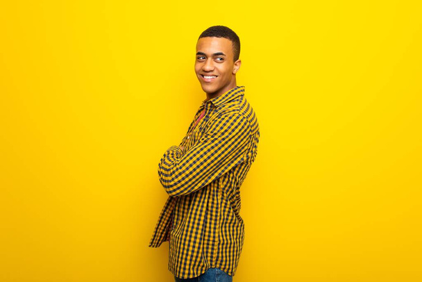 笑顔で肩を見て黄色背景に若いアフロ ・ アメリカ人 - 写真・画像