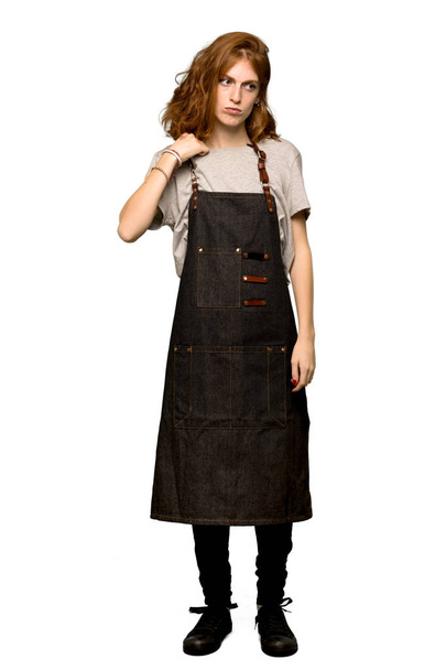 A full-length shot of a Young redhead woman with apron with a lot of heat over isolated white background - Photo, Image