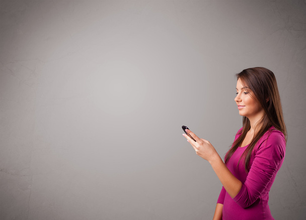 young lady standing and holding a phone with copy space - Foto, Imagem