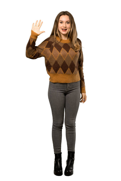 A full-length shot of a Teenager girl with brown sweater saluting with hand with happy expression over isolated white background - Фото, изображение