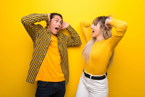 Молодая пара на ярком желтом фоне с удивлением и шокированным выражением лица
 - Фото, изображение