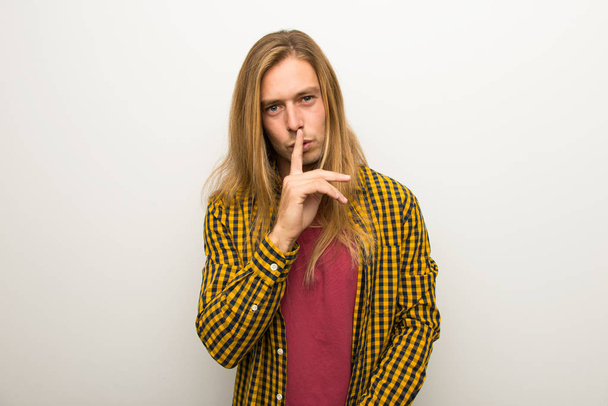 Blond man with long hair and with checkered shirt showing a sign of silence gesture putting finger in mouth - Fotoğraf, Görsel
