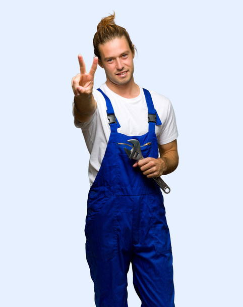 Workman smiling and showing victory sign on isolated background - Zdjęcie, obraz