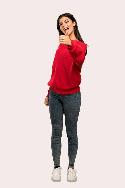 Un full-length shot di una ragazza adolescente con maglione rosso con i pollici in su perché qualcosa di buono è successo su sfondo isolato
 - Foto, immagini