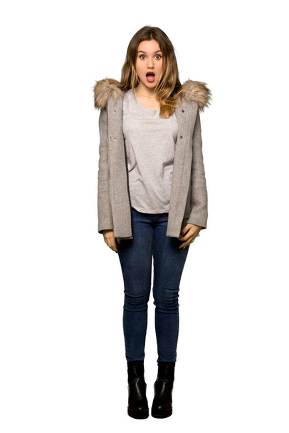 Una toma de cuerpo entero de una adolescente con abrigo y expresión facial impactada sobre un fondo blanco aislado
 - Foto, imagen
