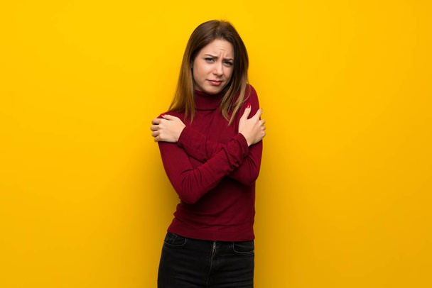 Woman with turtleneck over yellow wall freezing - Foto, Imagem