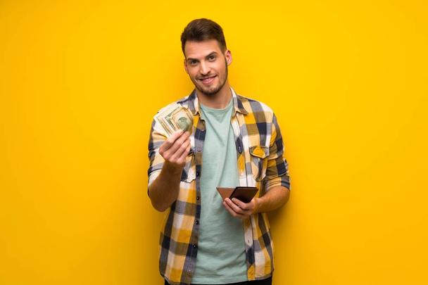 schöner Mann über gelbe Wand mit Geldbörse - Foto, Bild