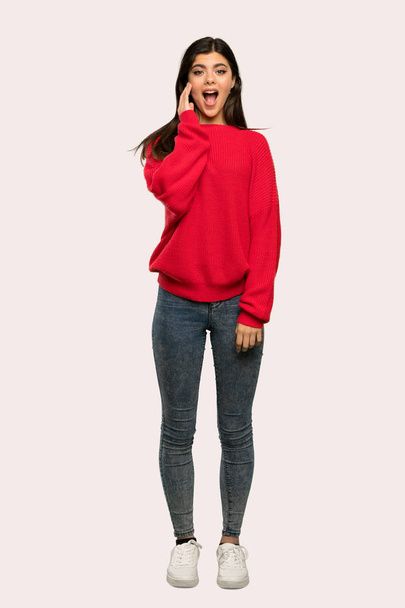 驚きとショックを受けた表情分離の背景の上に赤いセーターとティーンエイ ジャーの女の子のフルレングス ショット - 写真・画像
