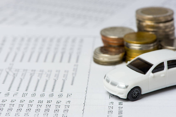 White car and coins on the account book in selective focus, Concept: Buy, new car, finance, investment. - Fotó, kép