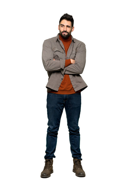 Full-length shot of Handsome man with beard with confuse face expression while bites lip on isolated white background - Photo, Image