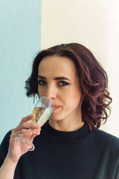 beautiful cheerful woman drinks champagne green blue background - 写真・画像