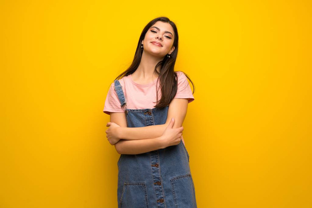 Teenager girl over yellow wall keeping the arms crossed in frontal position - Photo, Image