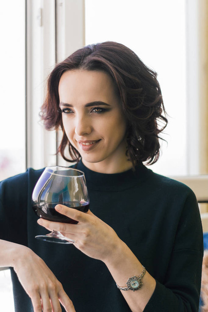 beautiful brunette woman with red wine glass near window - 写真・画像