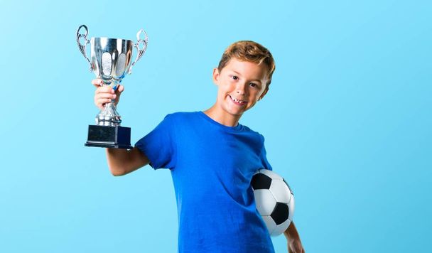 Ragazzo che gioca a calcio e tiene un trofeo
 - Foto, immagini