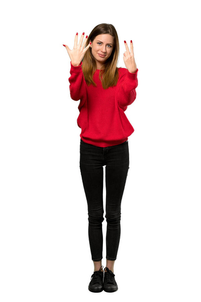 Ένα ολόσωμο πλάνο του μια νεαρή γυναίκα με το κόκκινο πουλόβερ που μετράει επτά με τα δάχτυλα πάνω από το απομονωμένο λευκό φόντο - Φωτογραφία, εικόνα