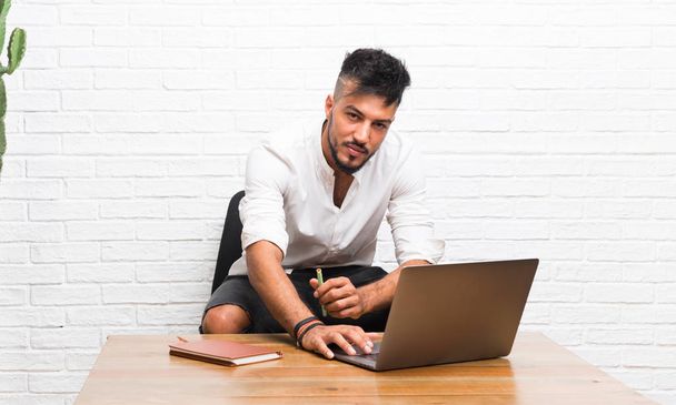 Hombre joven árabe usando un ordenador portátil en el interior
 - Foto, imagen