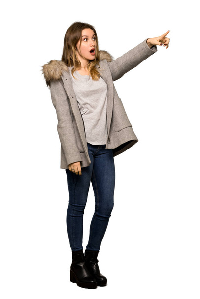 A full-length shot of a Teenager girl with coat pointing away on isolated white background - Foto, Bild